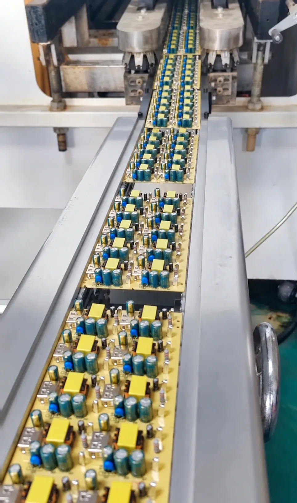 Charger PCB assemblies moving through an automated production-line conveyor